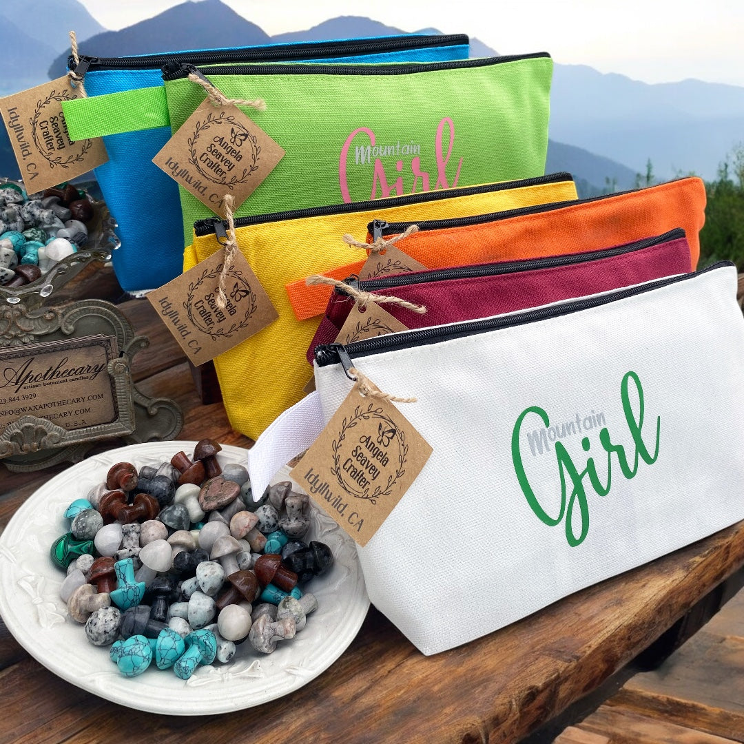 Mountain Girl Bundle Zipper Bags in assorted colors laying on wood with mountain skyline in the background
