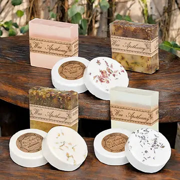 four bars of natural botanical soap and six botanical bath bombs sitting on wooden tables