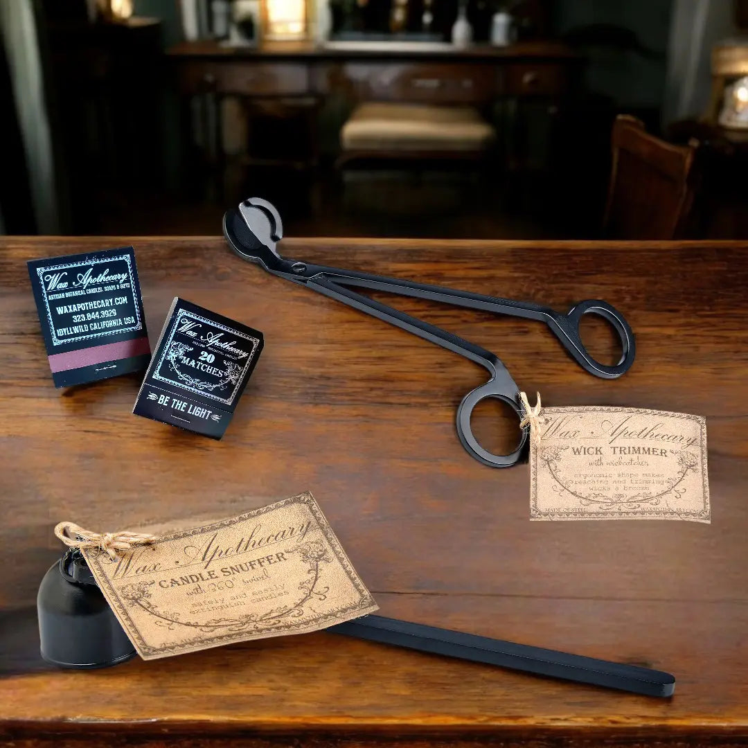 a wick trimmer, candle snuffer, and matchbooks sitting on a wooden desk