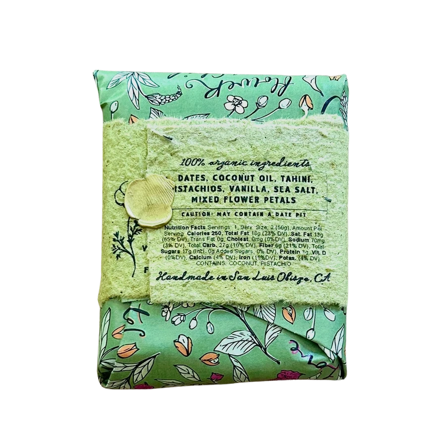 A folded bar of handmade soap in a mint green floral patterned wrapper, tied with a matching lace ribbon and a wooden bead, on a plain white background.