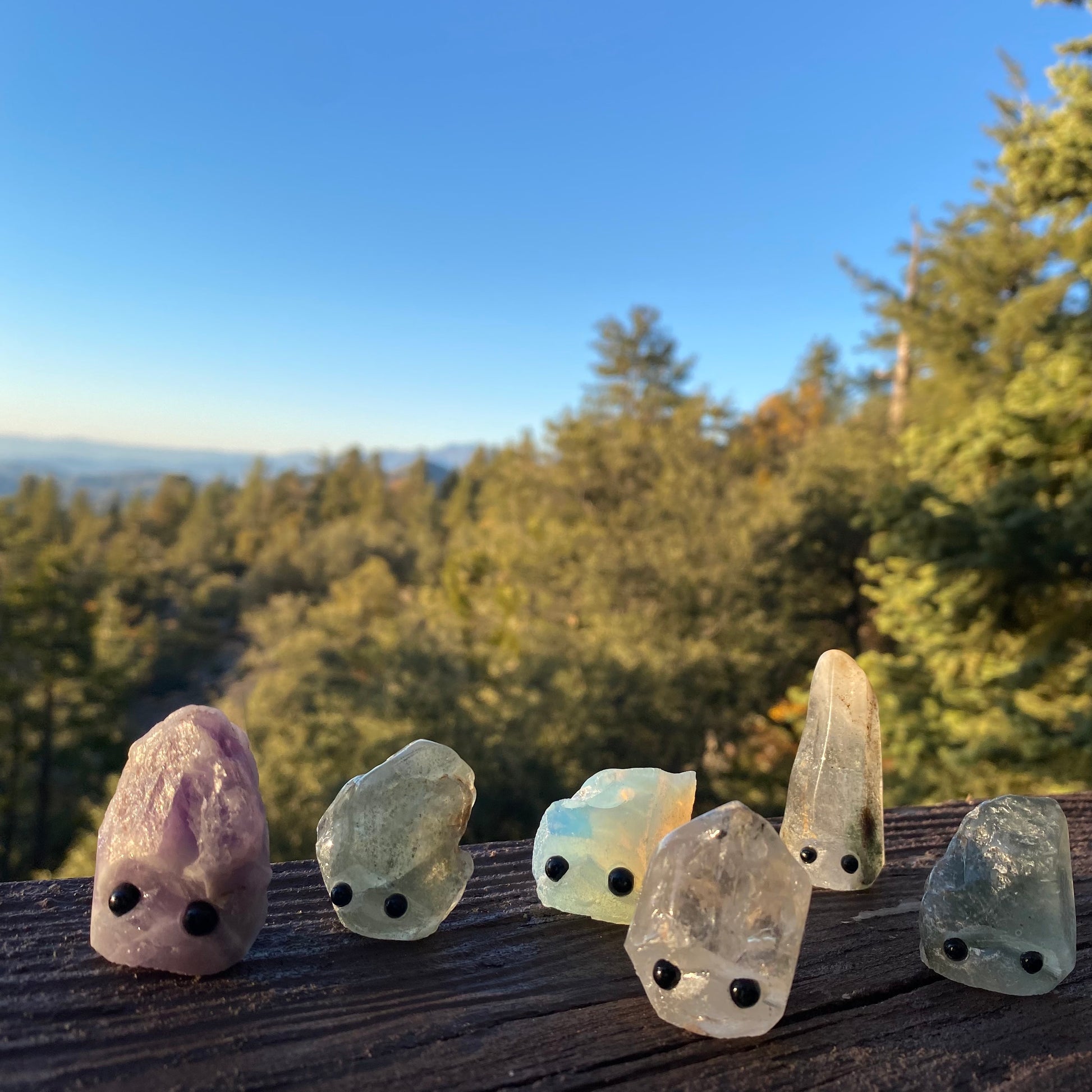 An assortment of rough cut gemstones with hand carved faces and black bead eyes.  Wax  Apothecary