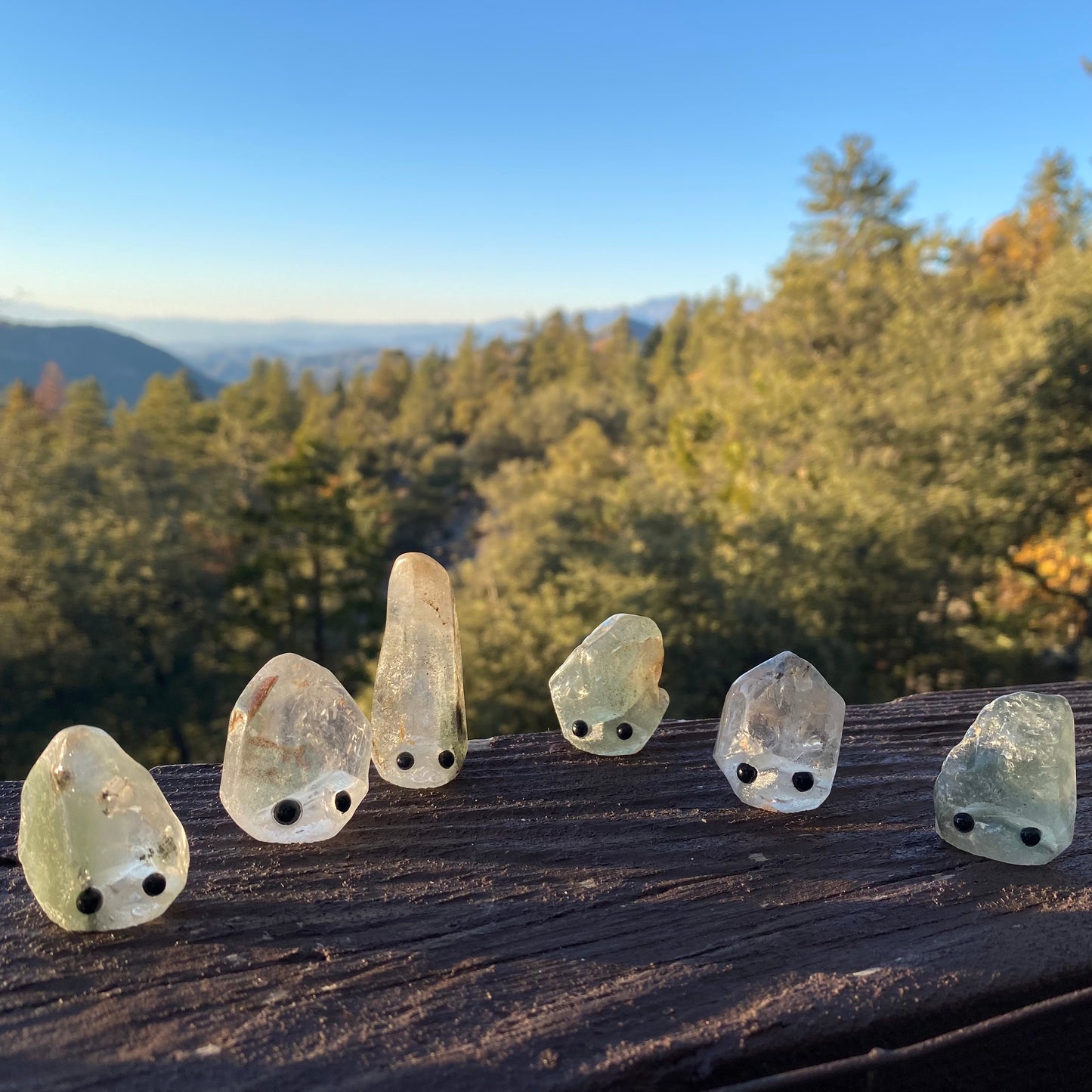 An assortment of rough gemstones with hand carved faces and black bead eyes.  Wax Apothecary