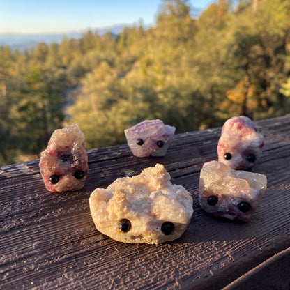 An assortment of rough gemstones with hand carved faces and black bead eyes.  Wax Apothecary