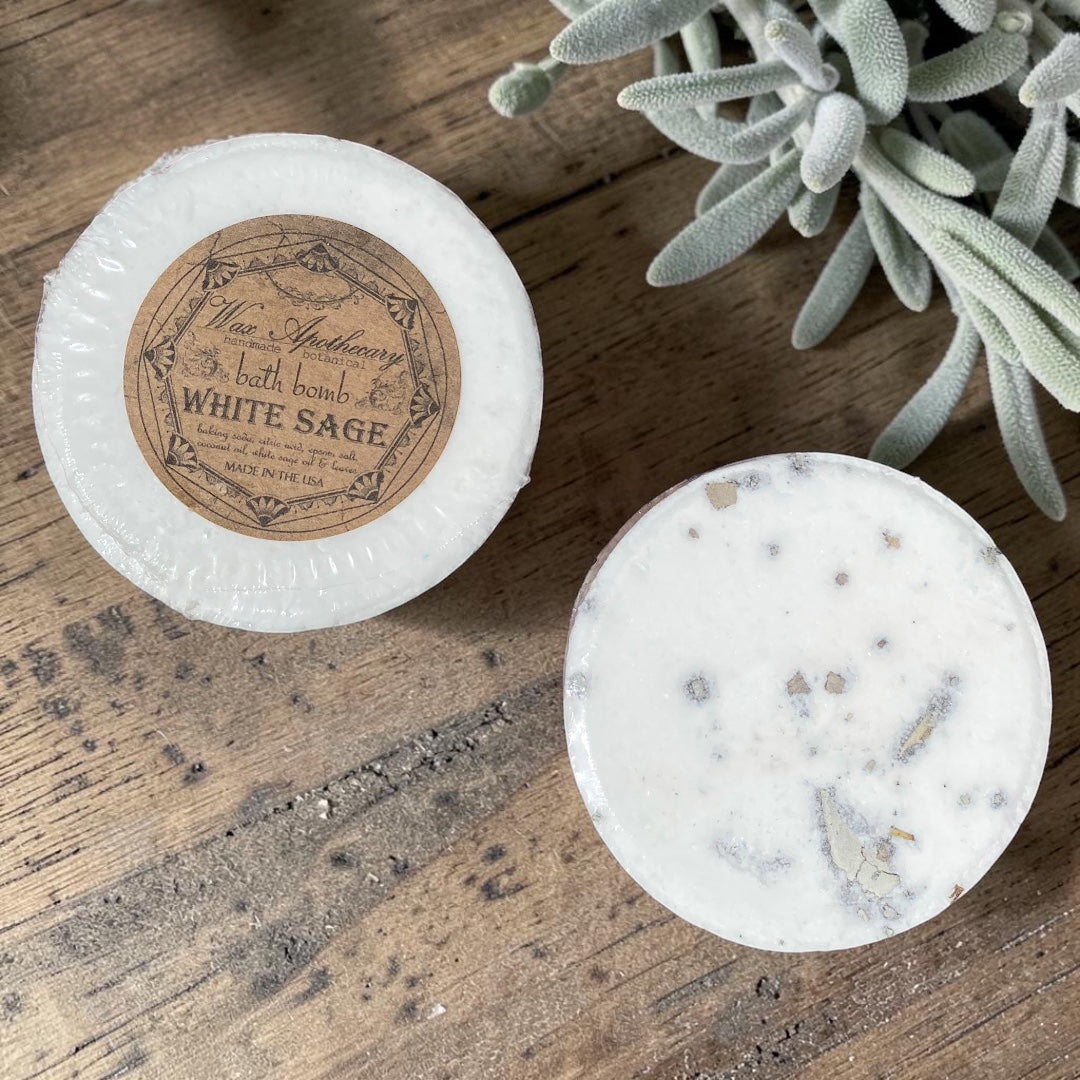 Two bath bombs on a wooden surface with a plant in the background